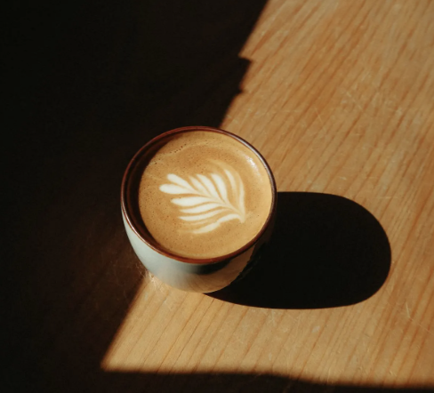 latte with leaf design on a wooden table